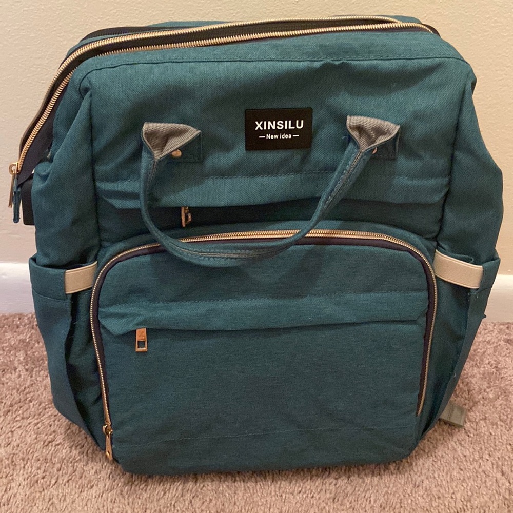 Green diaper backpack bag with pull out bassinet built in.